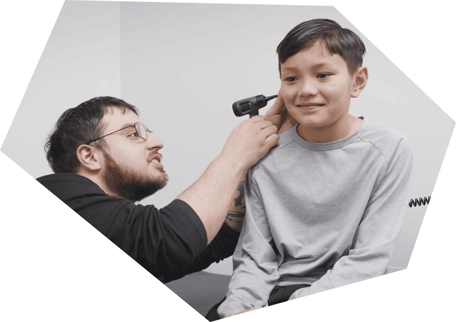 Clinician examining boys ear with otoscope