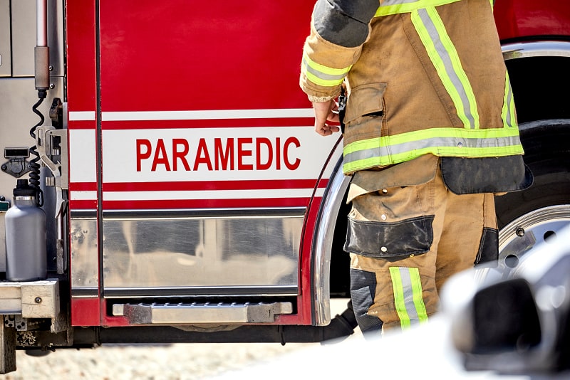 Firefighter standing beside paramedic truck Firefighter standing beside paramedic truck
